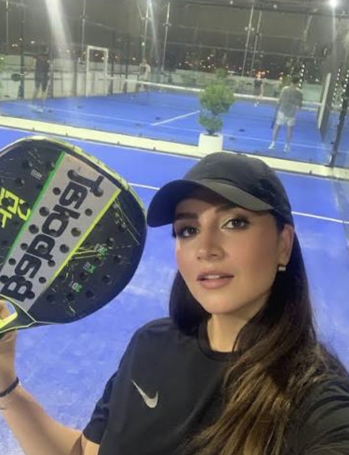 Player courtside with a padel racket at an evening meet